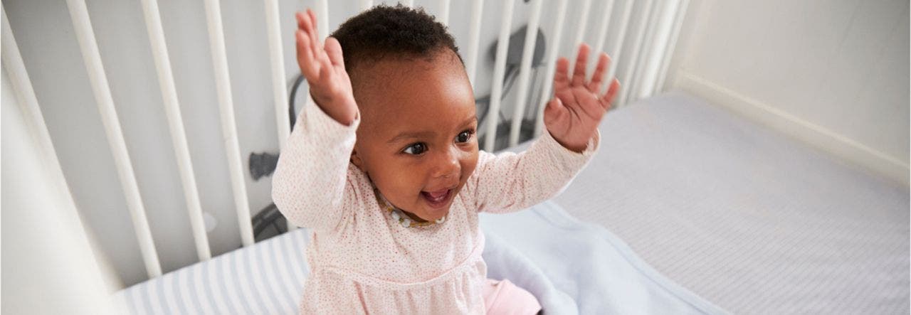 Happy baby playing on a Lullaby Earth non-toxic crib mattress