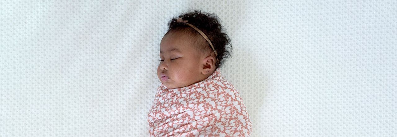 Baby wrapped in a swaddle blanket and sleeping safely