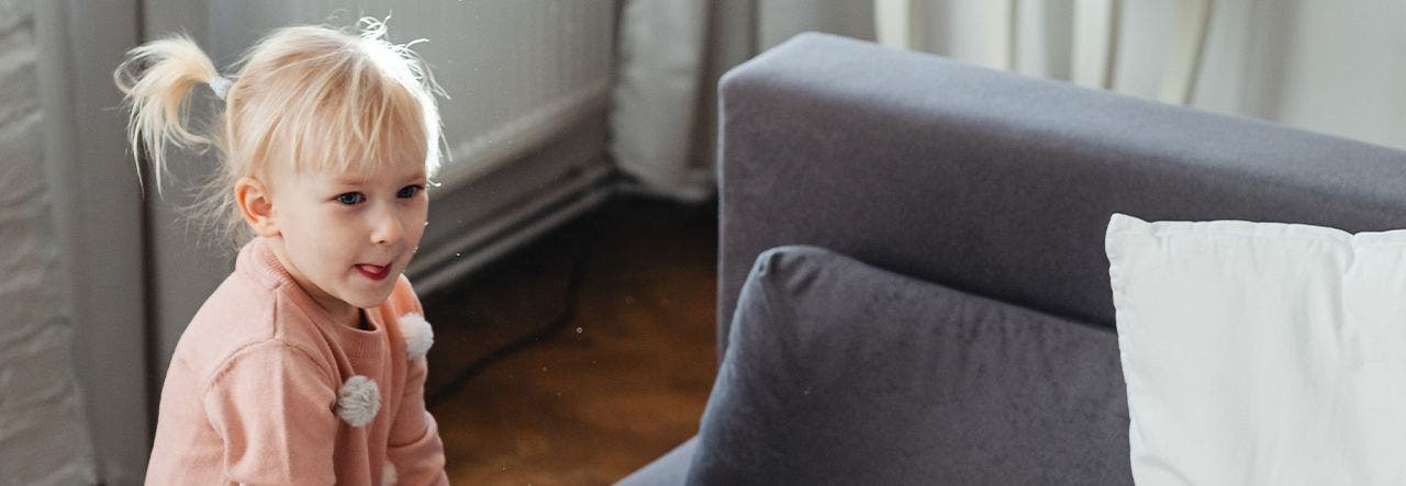 Wide-awake toddler leaning on the couch early in the morning