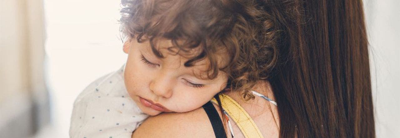 Mom holding a baby who's sleeping on her shoulder