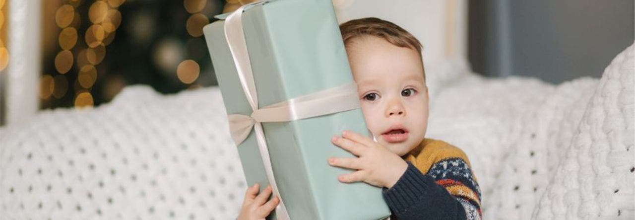 Toddler hugging a large wrapped gift