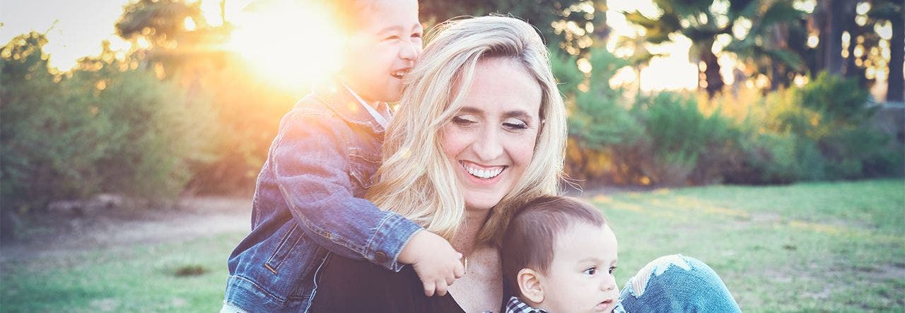 Smiling mom and two small children cuddling outside