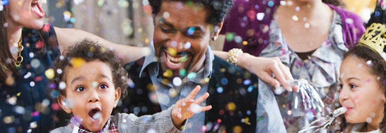 Parents and toddler celebrating new year's with confetti and noise makers