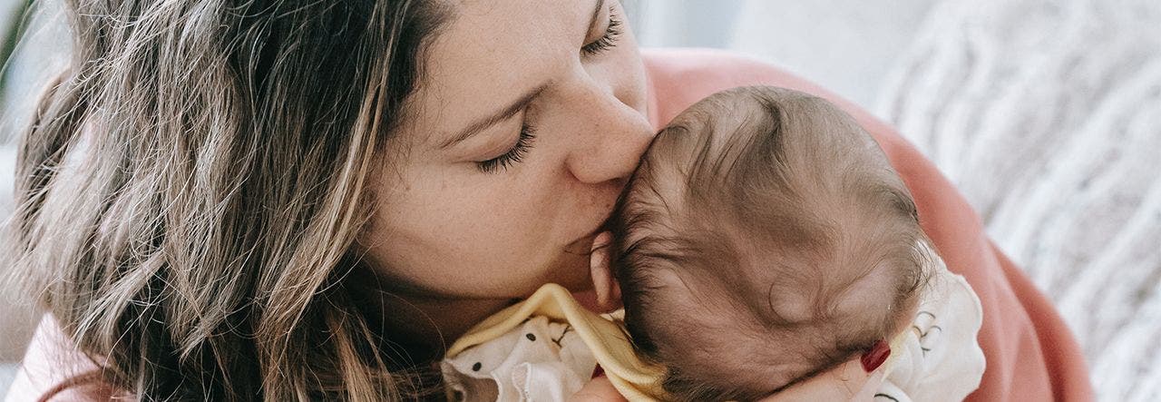 Mother kissing her newborn on head before going to work