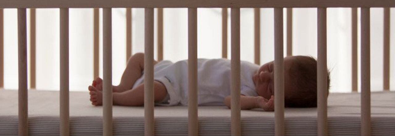 Baby lying on back and sleeping in the crib