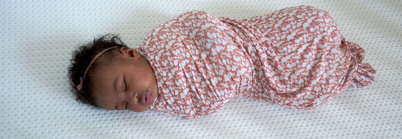 Baby sleeping peacefully in a pink swaddler