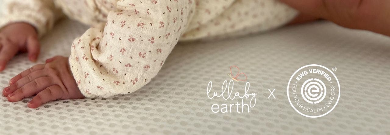 Baby enjoying tummy time on their EWG VERIFIED mattress, Lullaby Earth and EWG logos showing
