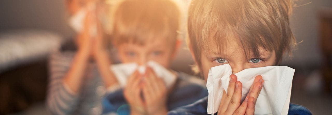 children sneezing into tissues