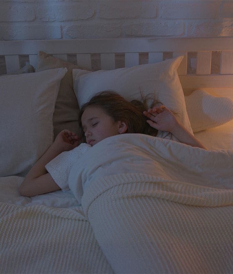 Child sleeping in bed with white sheets