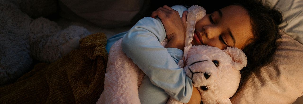 Young girl hugging her lovey in bed