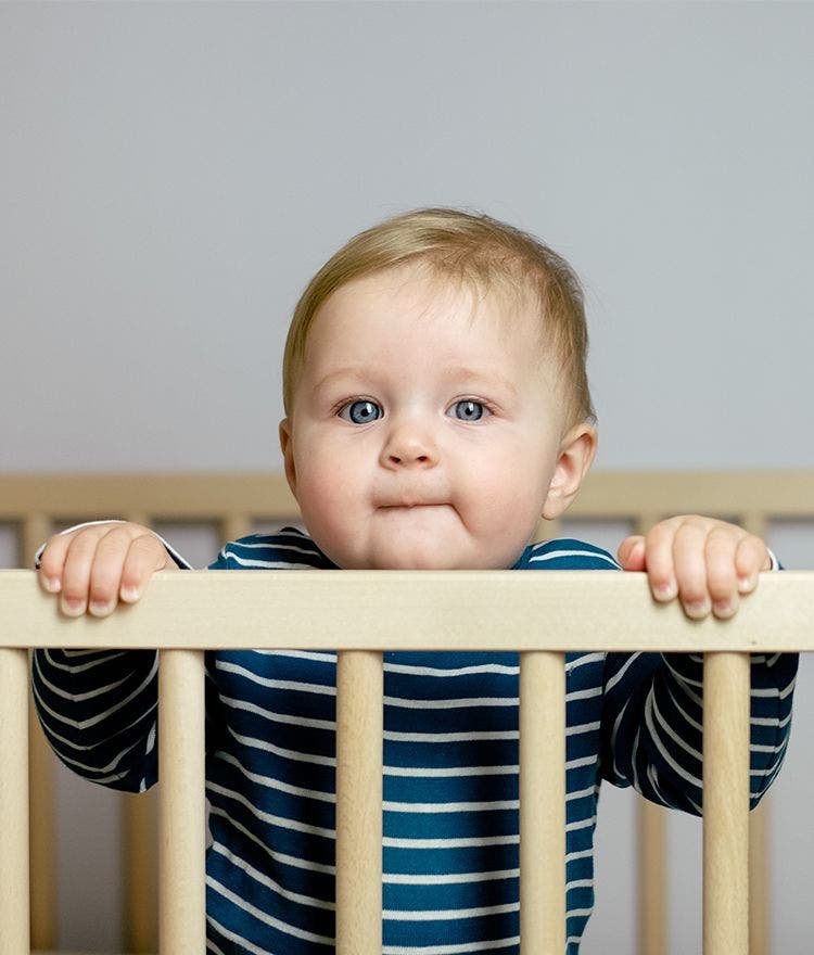 Toddler looking over side of crib standing up
