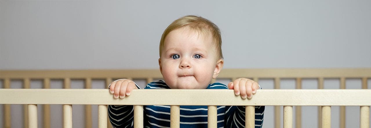 Toddler looking over side of crib standing up