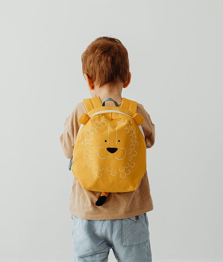 Red head child wearing yellow lion backpack