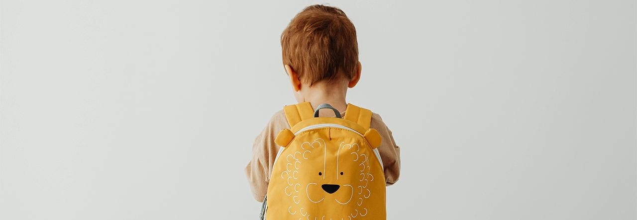 Red head child wearing yellow lion backpack