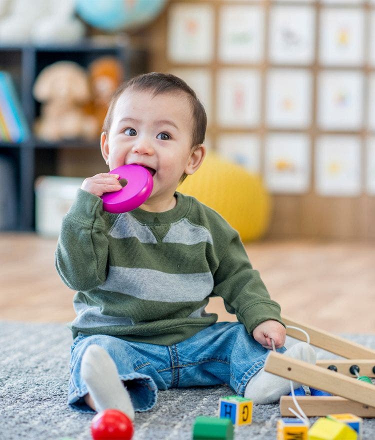 toddler chewing on plastic toy
