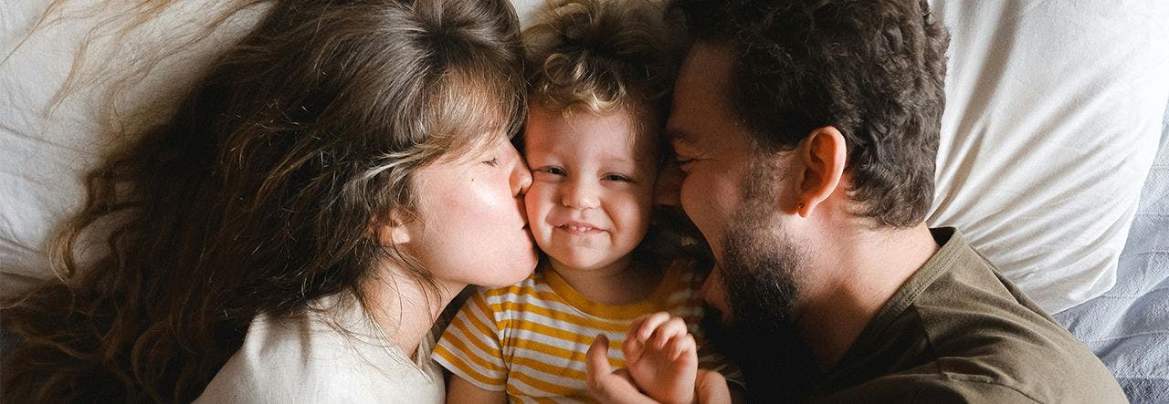 family of three laying in bed cuddling