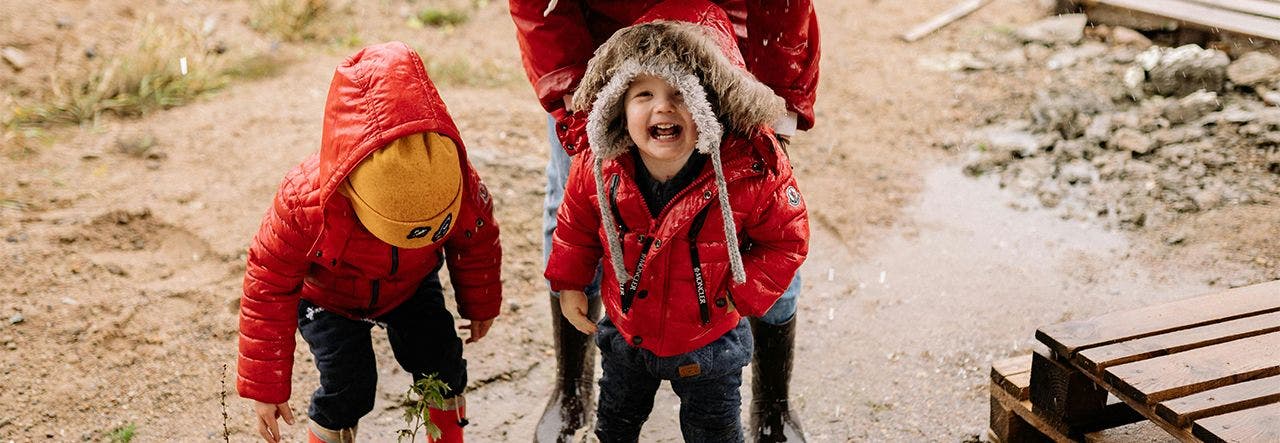 children in red raincoats jumping in puddles