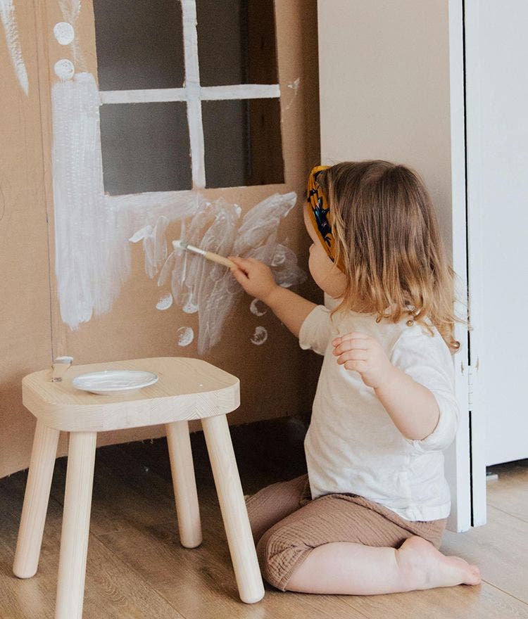 Child painting a cardboard wall