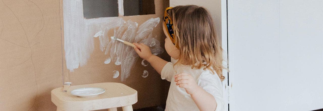 Child painting a cardboard wall