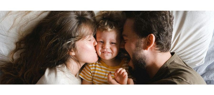family of three laying in bed cuddling