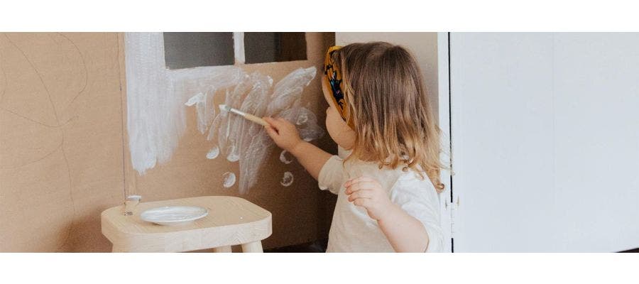 Child painting a cardboard wall