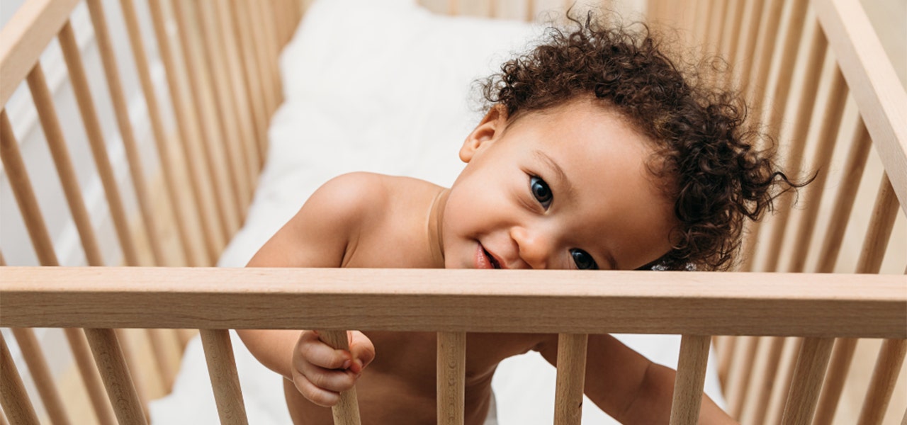 Smiling toddler standing up in their crib