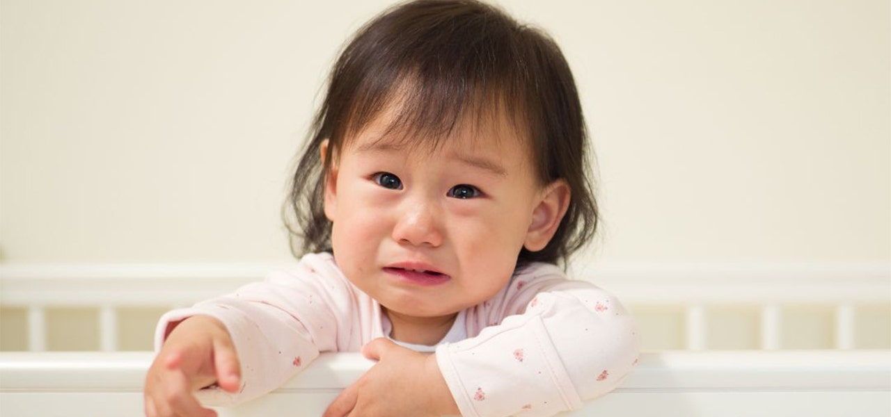 Toddler standing up in crib and looking upset