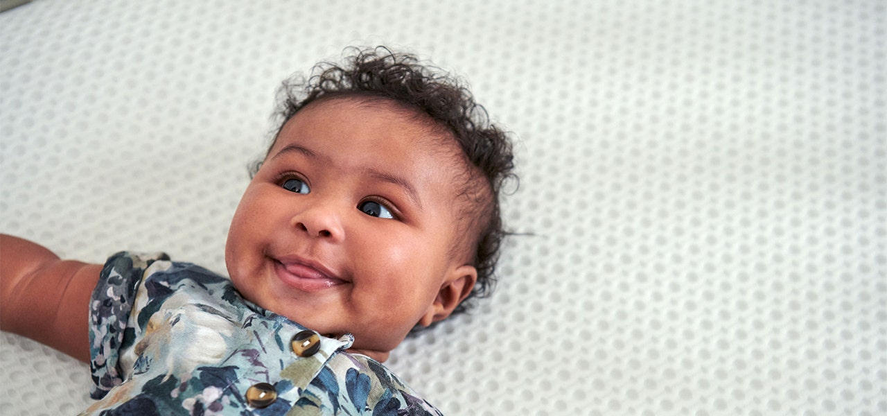Happy baby lying on a non-toxic crib mattress