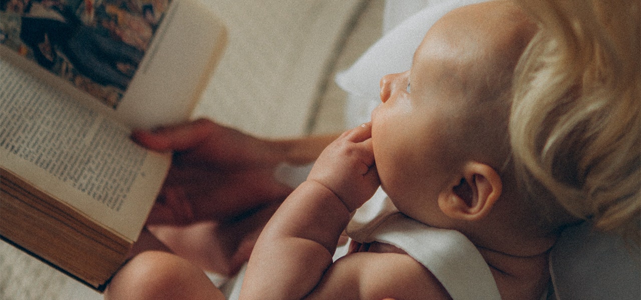 Parent reading a book to their baby