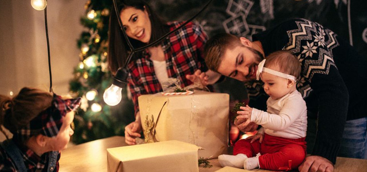 Parents and two kids unwrapping gifts wrapped in kraft paper