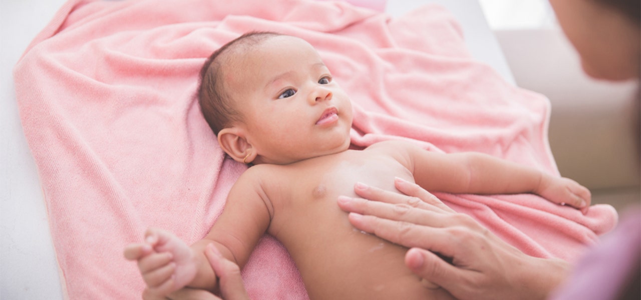 Parent massaging non-toxic cream on Baby's tummy