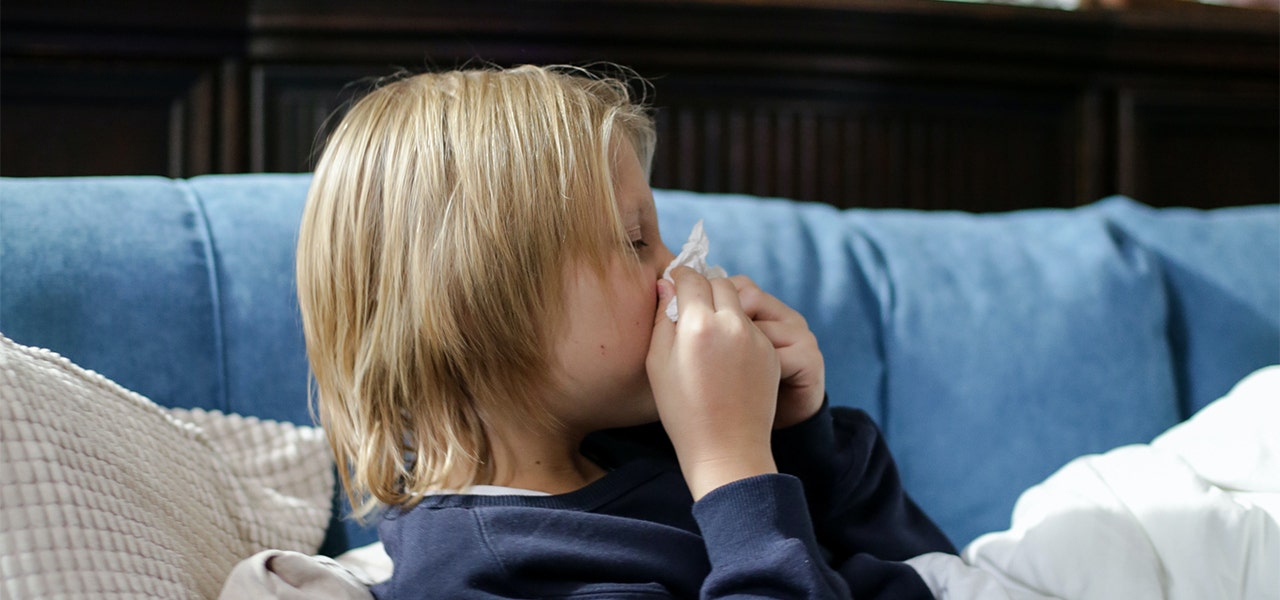 Child blowing their nose, experiencing side effects of poor indoor air quality