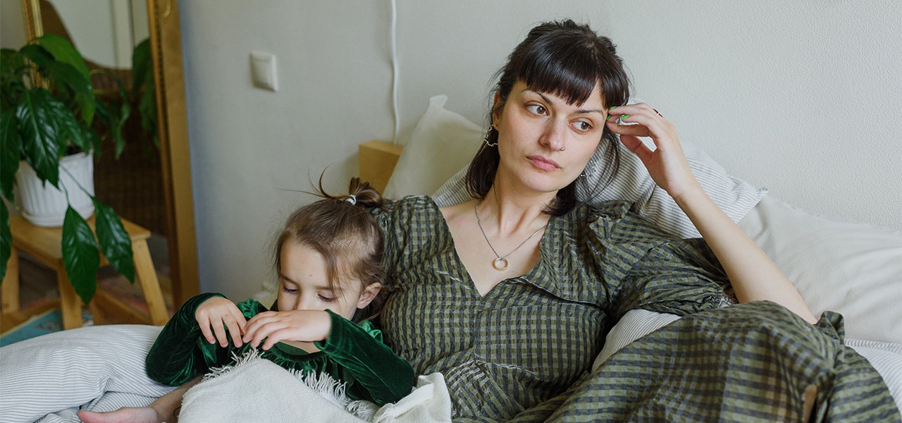 Mother safely holding her toddler but looking emotionally burdened