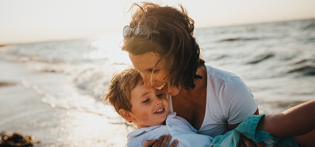 Mom and young child playing and laughing together on the beach
