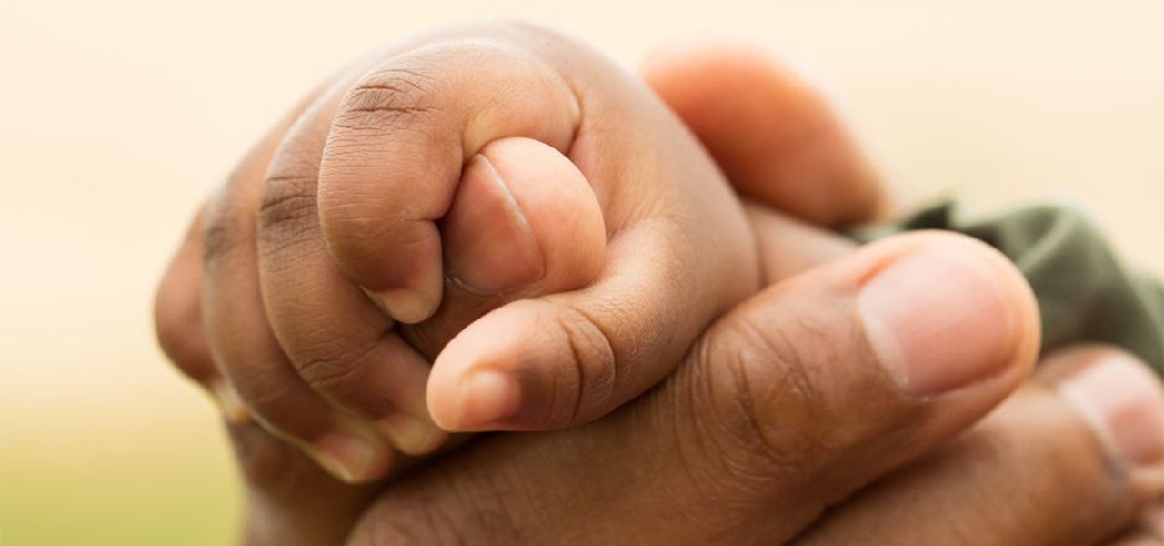 Baby's hand clutching parent's finger