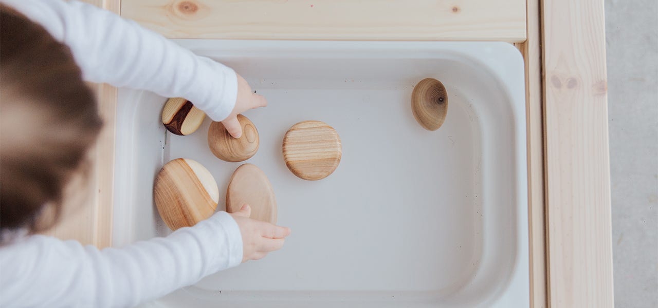 Toddler engaging in sensory play with wooden blocks and water