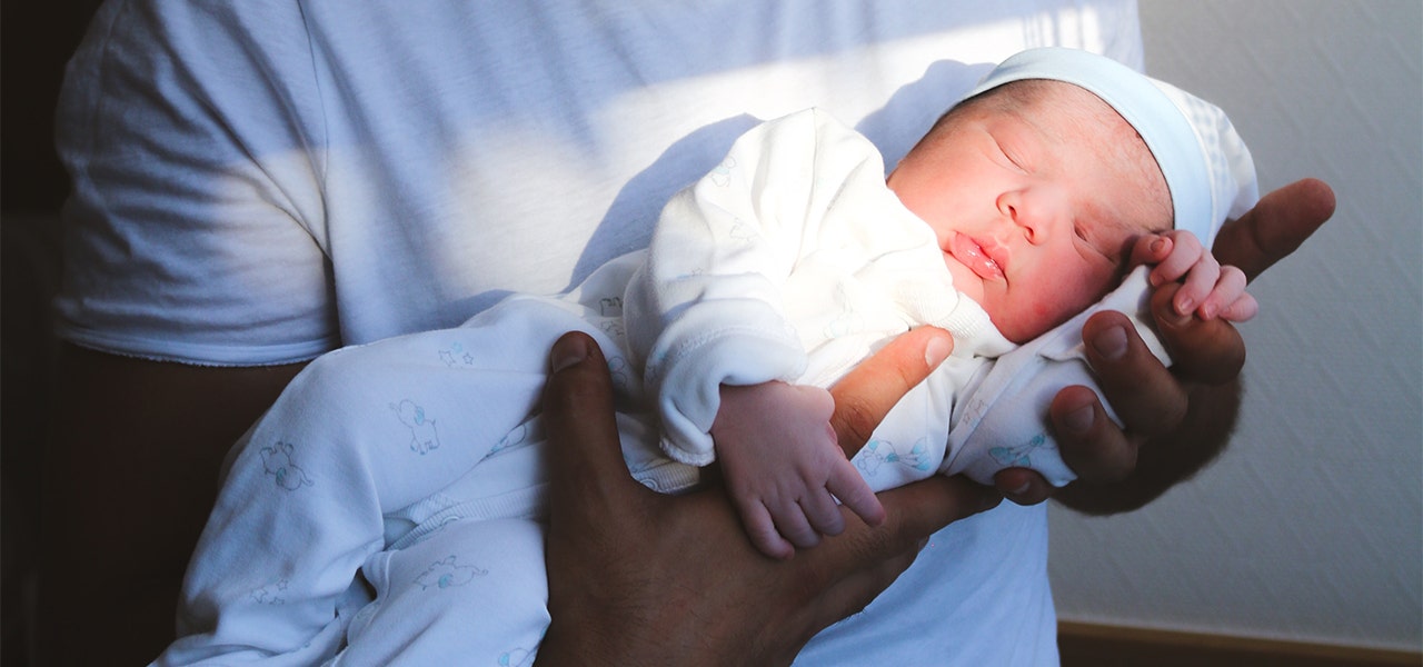 Newborn baby sleeping in their father's arms