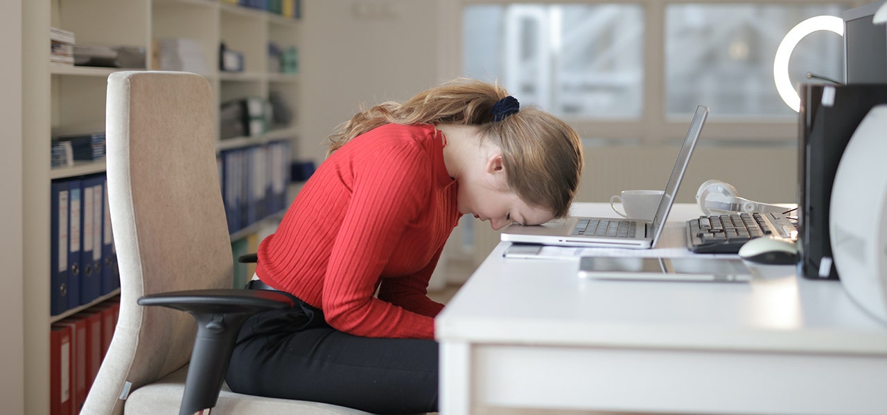 New mom with her head on her desk, struggling with mental health