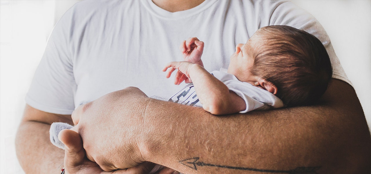 Father holding a sleeping newborn