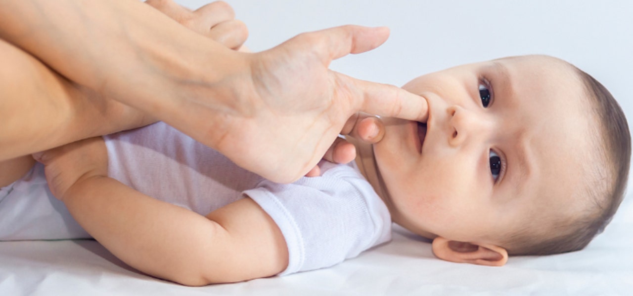 Parent rubbing their teething baby's gums to soothe them