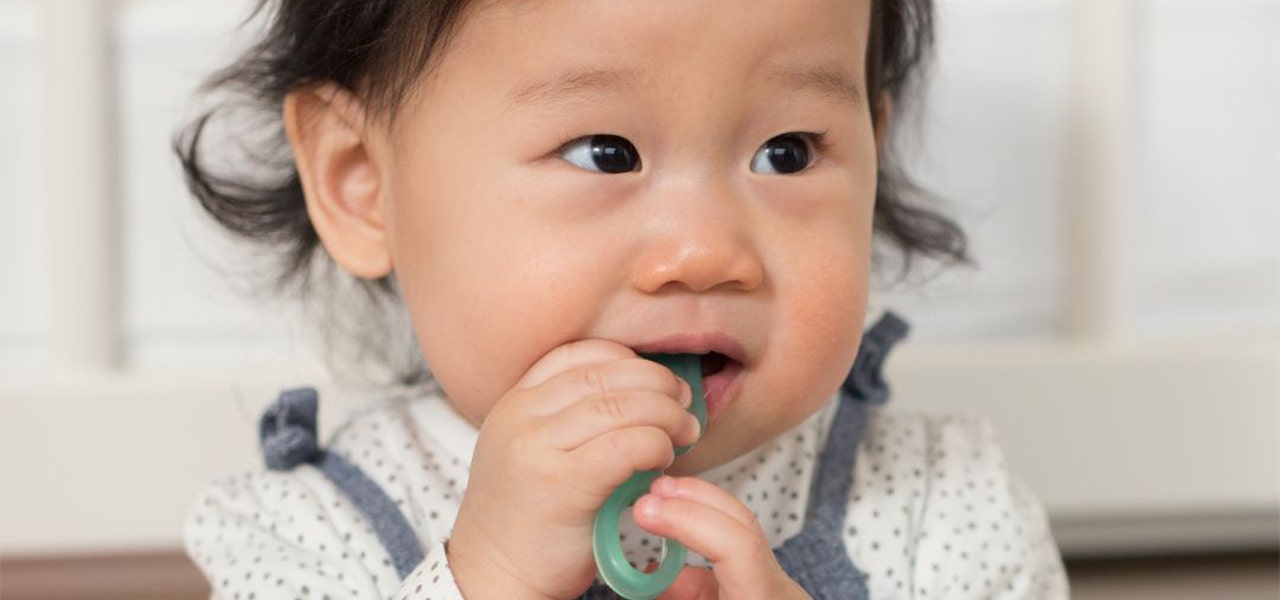 Teething baby chewing on a teething toy