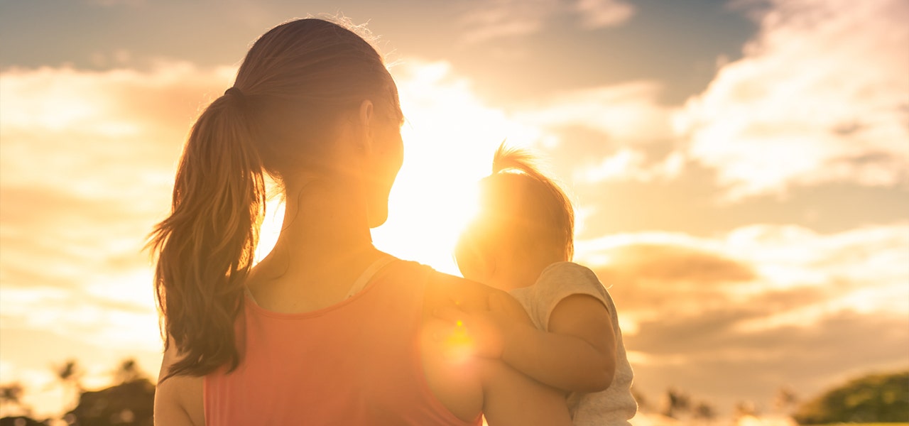 Woman holding baby and watching a sunset together