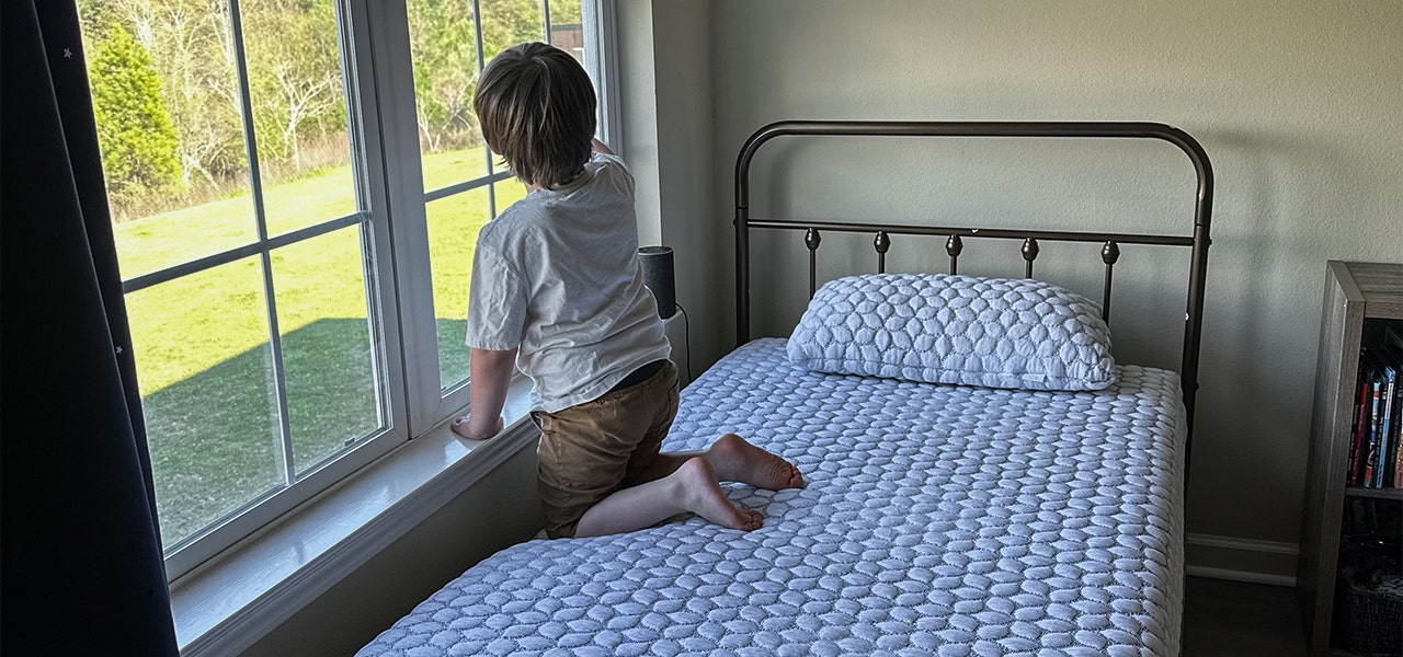 child on mattress looking out window