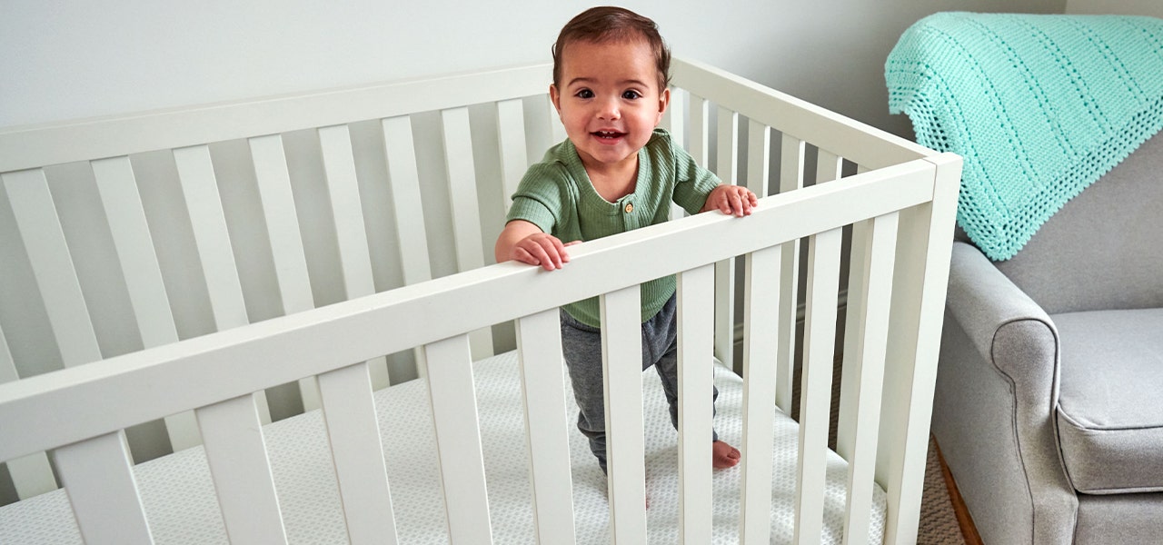 toddler standing in crib on waterproof crib mattress