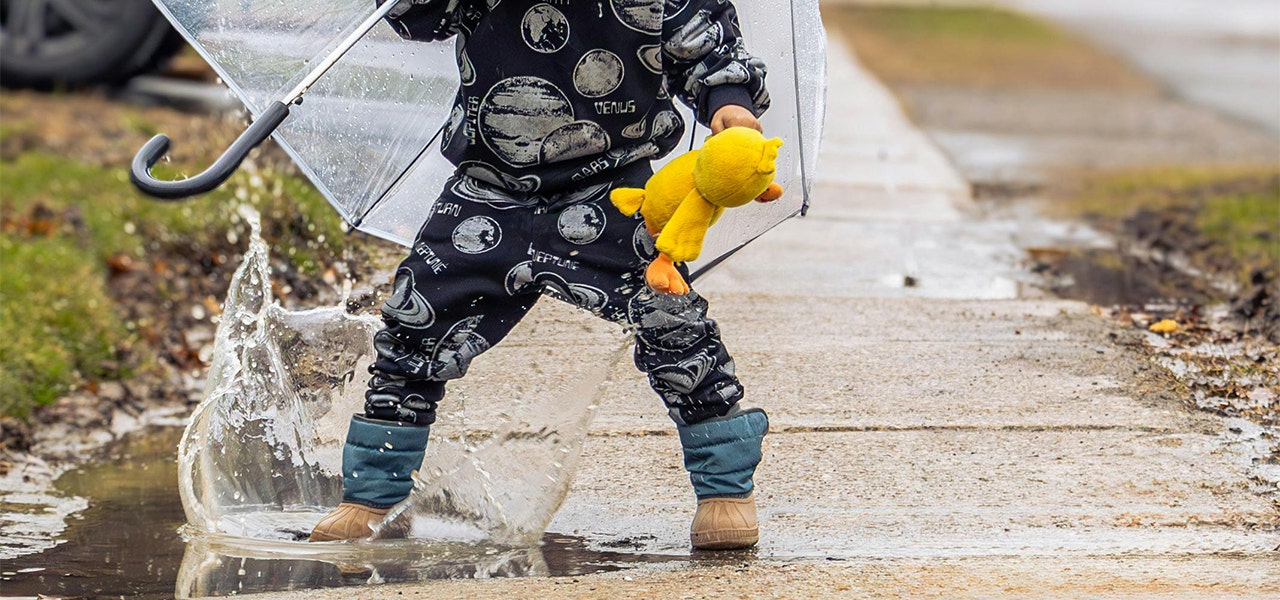 child in pajamas jumping in a puddle